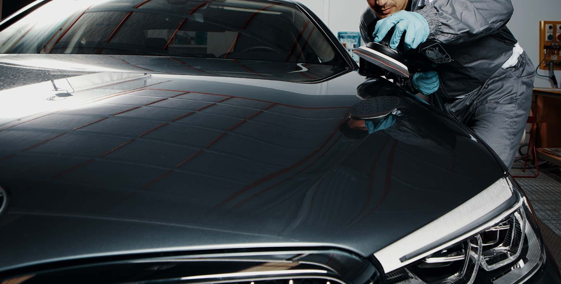 carro cinzento e homem com lixadeira na mão