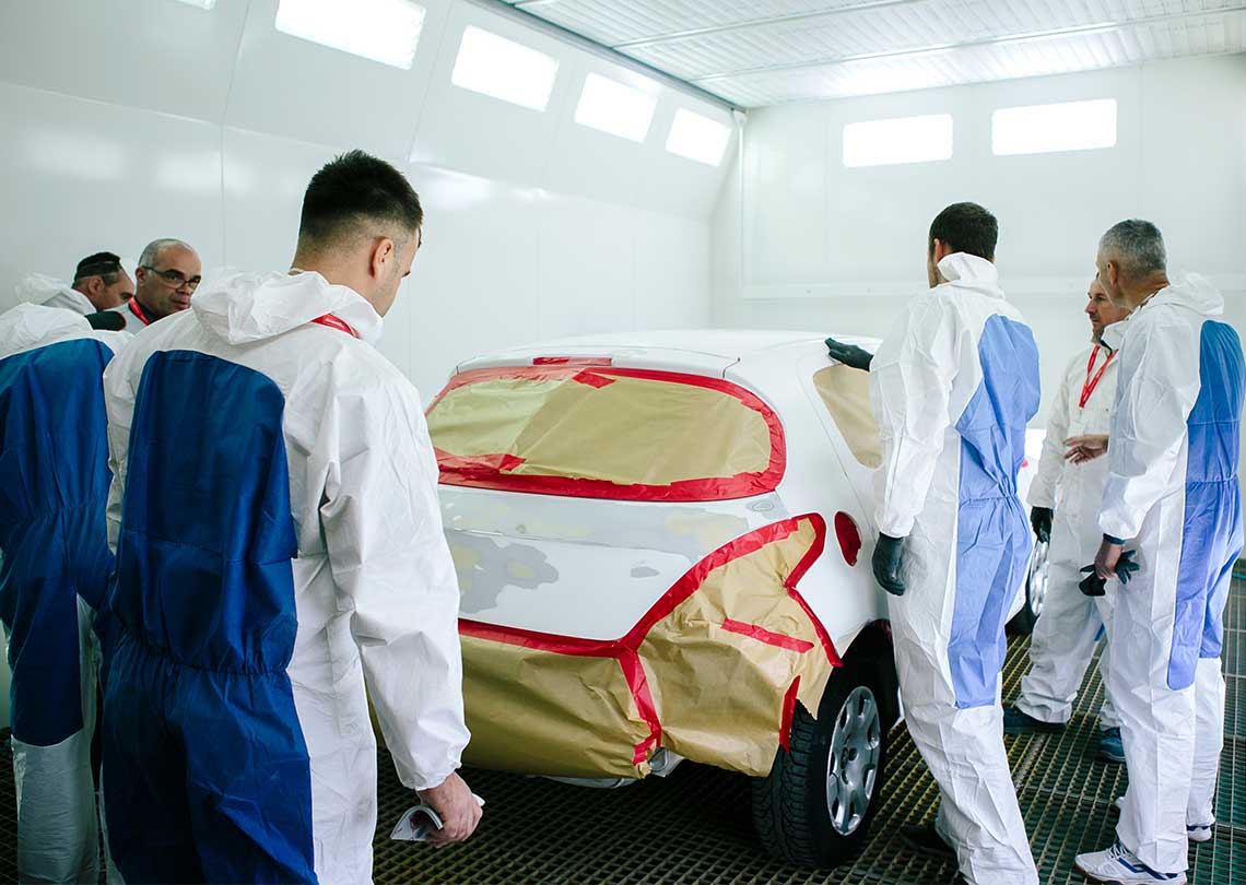 painters in spraybooth looking at white car with MTE-RED masking tape